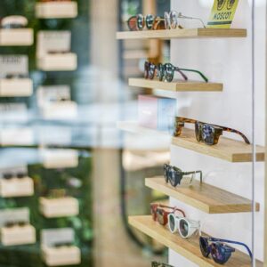 Stylish sunglasses neatly arranged on wooden shelves in a modern retail store setting.